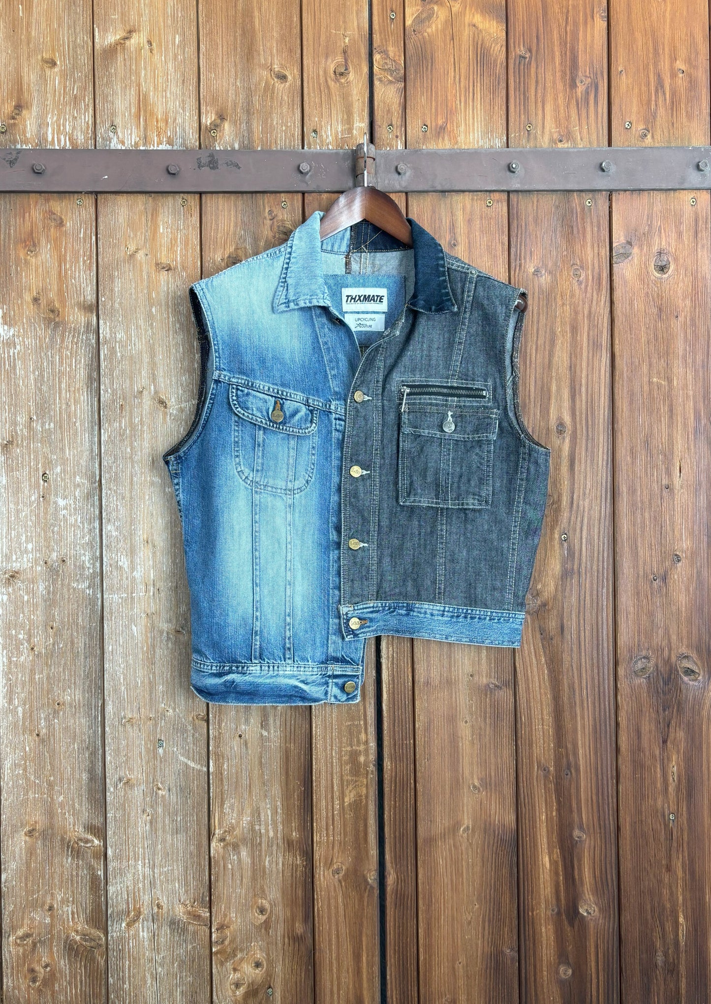 Eine einzigartige, asymmetrische Jeansweste, die aus einer hellblauen und einer dunkelblauen Jeansjacke zusammengesetzt ist. Die Weste hat einen hellblauen Abschluss, der die beiden Farben harmonisch verbindet. Die verfügt über einen Knopfverschluss und zwei Brusttaschen, die ebenfalls einen Knopfverschluss haben.