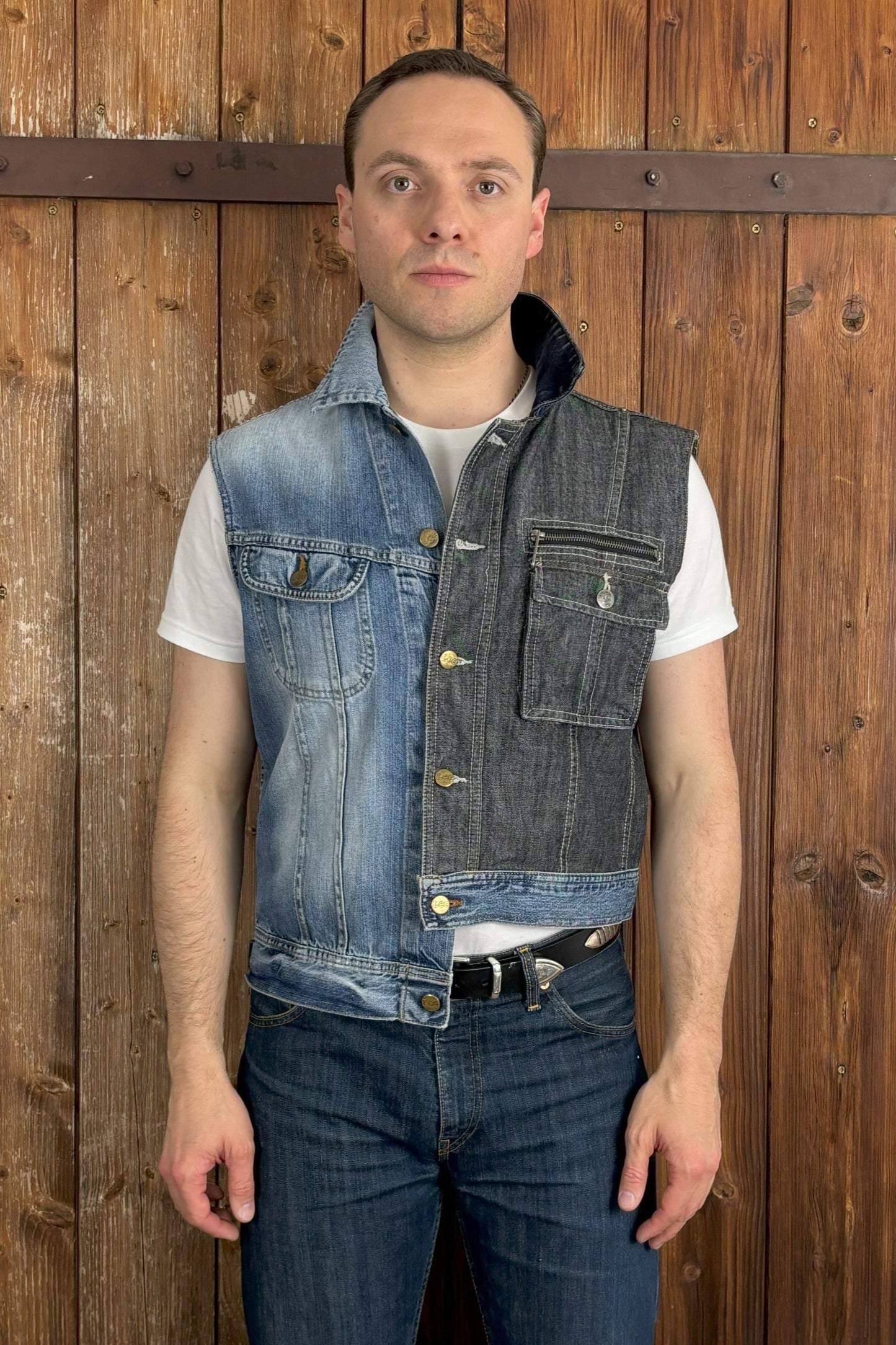 Eine einzigartige, asymmetrische Jeansweste, die aus einer hellblauen und einer dunkelblauen Jeansjacke zusammengesetzt ist. Die Weste hat einen hellblauen Abschluss, der die beiden Farben harmonisch verbindet. Die verfügt über einen Knopfverschluss und zwei Brusttaschen, die ebenfalls einen Knopfverschluss haben.